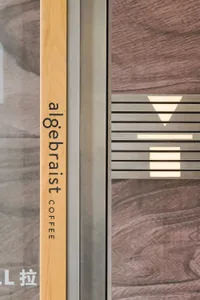 A wooden and metal lined coffee shop entryway with a light fixture above it.