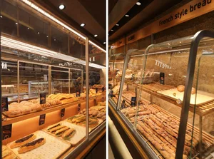 A modern bakery shop showcasing an array of freshly baked breads and pastries in a glass display case.