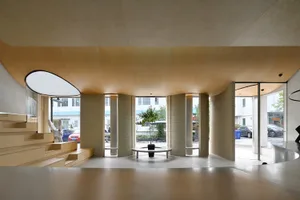 Interior design of a modern cafe lobby featuring a wood-paneled wall and a concrete floor.