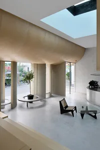A modern interior space with a curved concrete ceiling, large windows, and minimalist furniture.