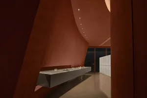 Modern museum exhibit hall with red curved concrete walls and marble floors.