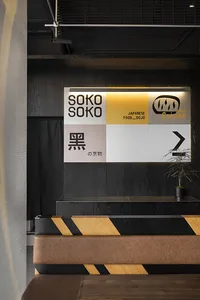 A modern restaurant interior with black timber paneling featuring the logo 'SOKO SOKO Japanese Food Dojo Cuisine'.