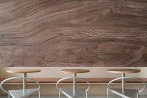 A modern restaurant interior with wooden walls, three wooden tables, and metal chairs.