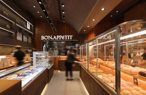 Modern retail bakery with glass showcases displaying various baked goods under warm lighting.