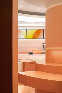 A coffee shop interior with orange walls and accents, featuring a counter and branding.