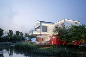 Modern restaurant exterior with white and red surfaces and outdoor seating area.