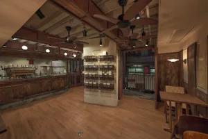 Industrial-style coffee shop interior with wooden floors, concrete walls, and metal fixtures.