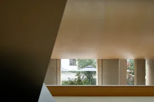 A modern interior space with wooden paneling and a view of an outdoor green space with a white umbrella.
