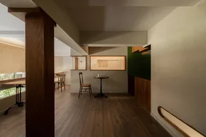 A modern coffee shop featuring wooden floors and concrete walls with a wooden bistro table and chairs.