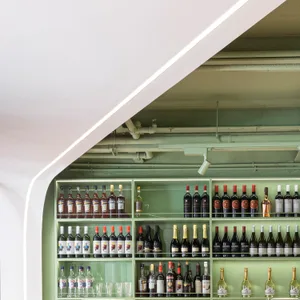 A modern green bar shelf filled with various drinks and glasses.