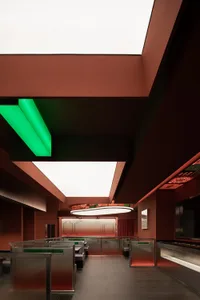 A modern, sleek restaurant with metallic frames and green and red lighting.