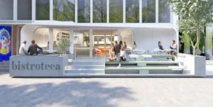 People sitting outside a modern restaurant with concrete and glass exterior.