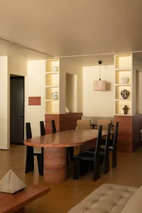 A minimalist dining room with a sandstone table and black chairs.
