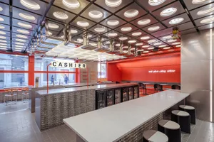 A modern cafe bar interior with metallic finishes, red tiled walls, and glass elements.