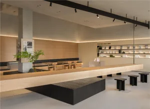 Modern coffee shop interior with wooden tables, concrete accents, and a minimalist design.