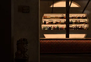 A bar interior with concrete finishes and shelves filled with bottles.