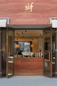 Modern storefront with a marble facade and open glass doors.