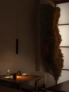 A minimalist dining room with wooden furniture and fabric wall hanging.
