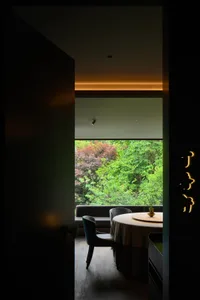 A modern, minimalist restaurant interior with a circular table and chairs, illuminated by soft, ambient lighting.