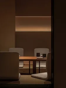 A minimalist restaurant interior with wooden furniture and warm lighting.