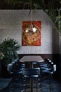 Industrial-style bar with metal stools, leather seating, and wooden table and chairs.