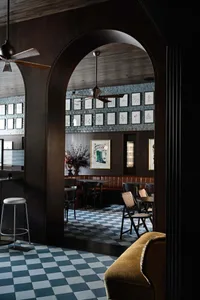 Industrial restaurant interior with brick walls, brown leather booths, wooden tables, and metal accents.