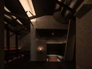 Industrial-style restaurant interior with concrete walls, exposed beams, and seating areas.