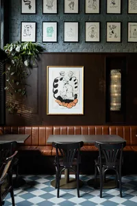Restaurant interior with industrial design elements, wooden tables, leather booths, and brick walls.