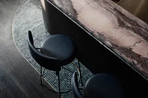 Modern bar counter made of marble with black leather stools