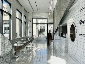 Modern cafe interior with white tiled floor, concrete walls, and sleek furniture.