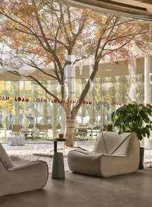 A modern lobby area with glass walls and furniture, featuring a relaxing seating area with comfortable sofas and a small tabl