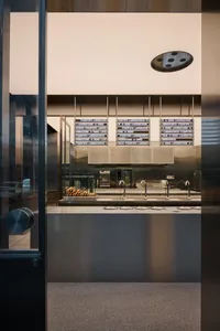 A modern restaurant with a metallic counter and glass display case.