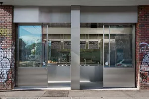 A modern retail storefront with glass doors and stainless steel accents.