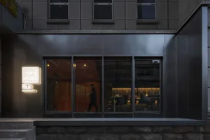 A modern storefront with a black metal frame and glass panels at night.