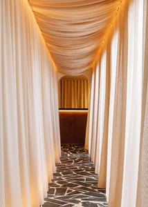 A serene, elegant corridor lined with draped fabric curtains.