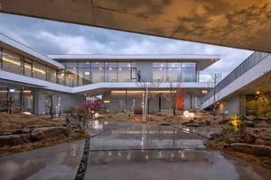 Modern office courtyard featuring concrete, glass, and rock elements.