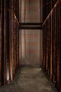 Decorative bamboo corridor with textured floor and light filtering through curtains.