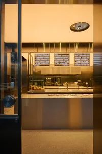 A modern storefront with a metallic glass door, featuring illuminated signage and sleek design elements.
