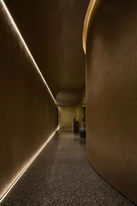 A modern, minimalist corridor with curved concrete walls and lit edges, featuring polished concrete floor.