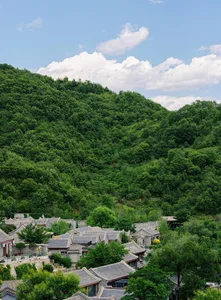A cityscape featuring greenery and stone structures under a clear blue sky.