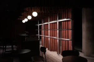 Modern industrial metal cafe bar with red curtains, white spherical lights, and minimalist design.