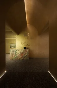 A minimalist lobby featuring a marble counter, floral arrangements, and warm lighting.
