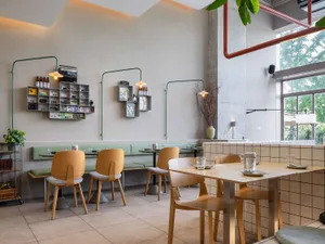 A modern restaurant with wooden furniture, concrete walls, and glass elements.