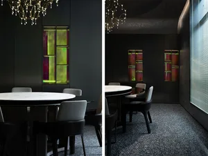 A modern dining room featuring a marble table and chairs, with a glass cabinet displaying colorful artworks.