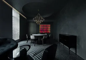 A modern residential dining room with concrete walls, a round table, and a chandelier.