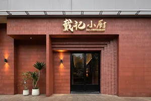 A brick restaurant exterior with a black door and gold lettering.