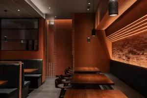A cozy restaurant interior with brick tiles on the walls and wooden tables and chairs.