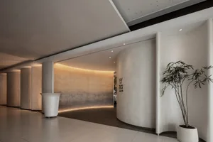 Modern, minimalist entryway featuring curved, concrete pillars with warm, ambient lighting.