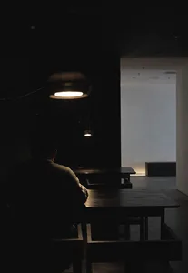 A minimalist cafe interior featuring wooden tables and subdued lighting.