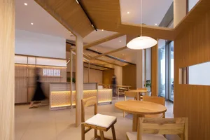 A modern restaurant interior with wooden tables, chairs, and lighting fixtures.